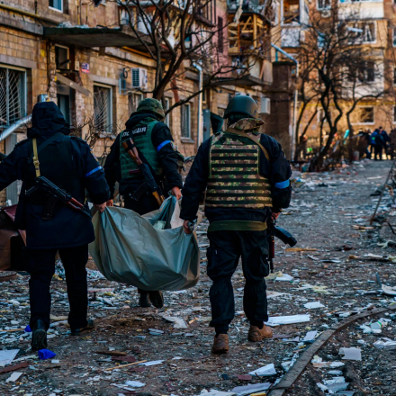 Polizisten tragen eine Leiche weg, nachdem ein Wohngebiet in Kiew, Ukraine, von einem russischen Raketenangriff getroffen wurde
