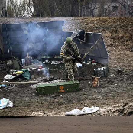 An Ukrainian soldier walks next to a camp fire at a frontline, northeast of Kyiv