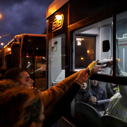 Volunteers offer food to people fleeing Ukraine after the Russian invasion, as they wait in a bus near the North Railway Station in Bucharest, Romania