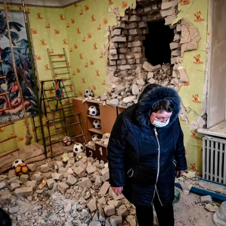 A woman stands among debris after the reported shelling of a kindergarten in the settlement of Stanytsia Luhanska