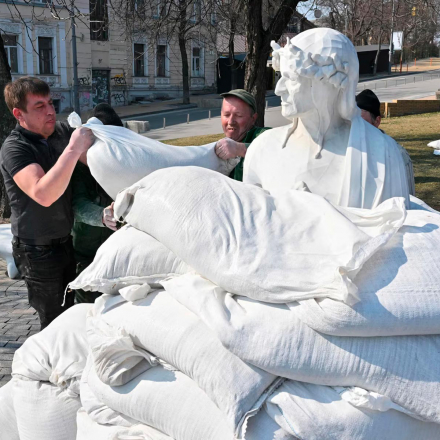 Stadtarbeiter verwenden Sandsäcke, um ein Denkmal für den italienischen Dichter, Schriftsteller und Philosophen Dante Alighieri abzudecken, um es vor russischem Beschuss in Kiew zu schützen