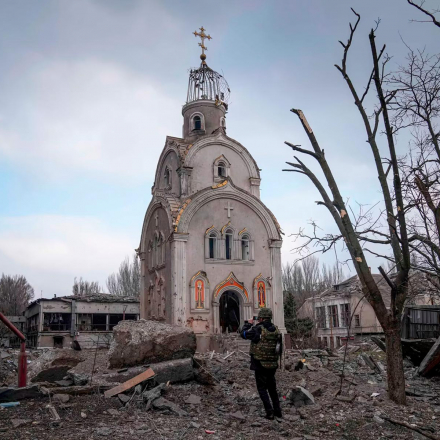 A Ukrainian serviceman takes a photograph of a damaged church after shelling in a residential district in Mariupol