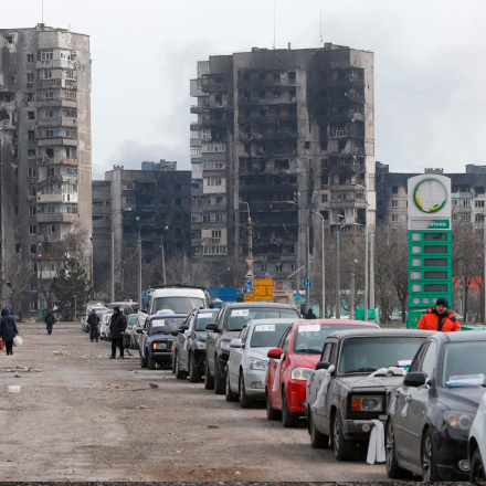 Eine Ansicht zeigt eine Reihe von Autos in der Nähe von zerstörten Wohnblöcken, während Evakuierte die belagerte Hafenstadt Mariupol verlassen