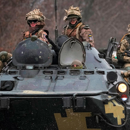 Ukrainische Soldaten sitzen auf gepanzerten Mannschaftstransportern, die auf einer Straße in der Region Donezk fahren