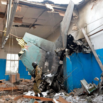 A member of the Ukrainian Territorial Defense Forces walks near the remains of a Russian aircraft which crashed into a technology manufacturing building in Kharkiv
