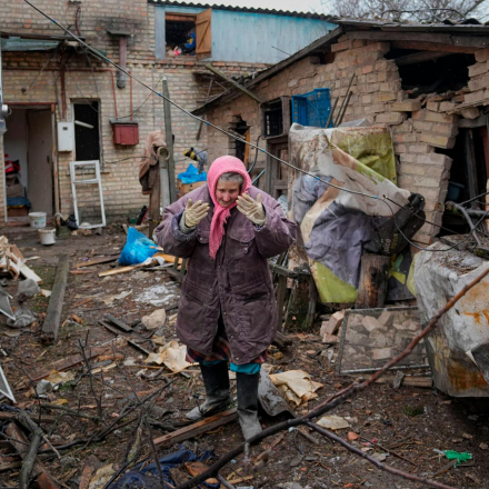 A woman stands in the backyard of a house damaged by a Russian airstrike, according to locals, in Gorenka, outside the capital Kyiv, Ukraine
