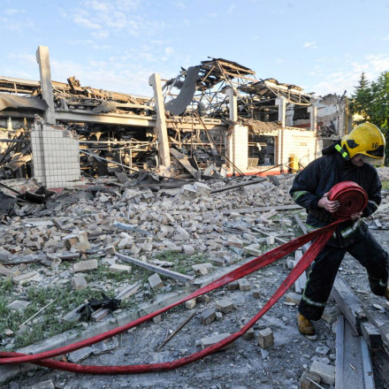 A firefighter in Kyiv pulls a hose near the production shop of the Darnytskyi freight car repair plant