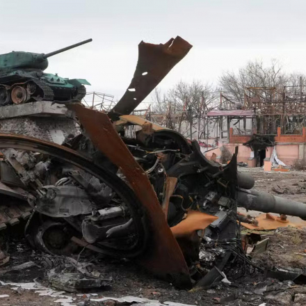 Local residents pass by a damaged Russian tank in a town east of Kyiv