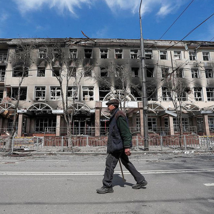 A resident walks near a building destroyed in the course of the Ukraine-Russia conflict, in the southern port city of Mariupol, Ukraine