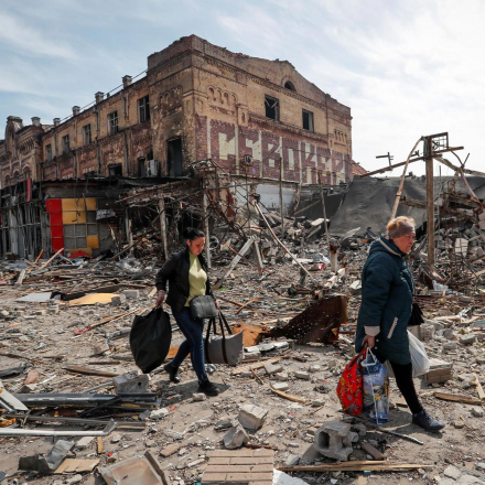 Residents carry their belongings near buildings destroyed in the course of Ukraine-Russia conflict, in the southern port city of Mariupol