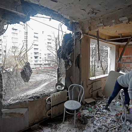 A woman inspects debris inside an apartment of a residential building, which locals said was damaged by recent shelling