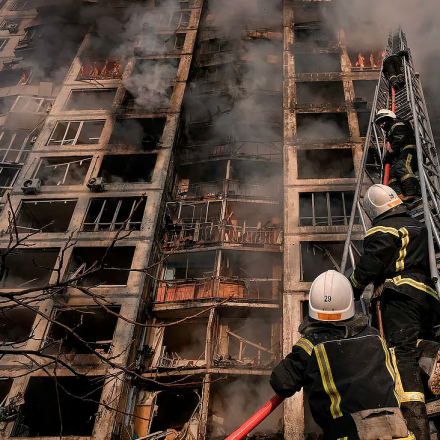 Firefighters climb a ladder while working to extinguish a blaze in a bombed out apartment building in a residential area of Kyiv