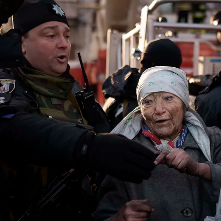 Einer älteren Frau wird von Polizisten geholfen